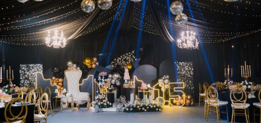 Black-draped party venue features mirrored disco balls, blue spotlights, gold seating, flowers, and a glowing 15.